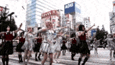 a group of people are dancing in front of a building that says aoki on it