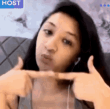a woman is sitting on a couch wearing headphones and making a face .