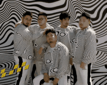 a group of men are posing in front of a wall that has a pattern of waves