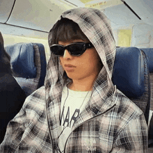 a person wearing sunglasses and a plaid jacket with the word wars on the front