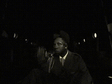 a black and white photo of a man in a suit sitting on a chair