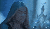a woman with long blonde hair is standing in front of a statue in a dark room with her eyes closed .