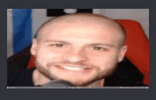 a bald man with a beard is smiling in a close up of his face .