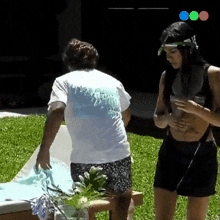 a man and a woman are standing in the grass and the man is wearing a white shirt with a blue flame on the back