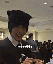 a man wearing a cat ear hat is standing in a room with a crowd of people .