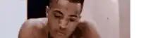 a shirtless man with a tattoo on his face is taking a bath .