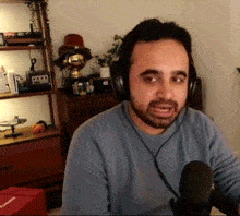 a man wearing headphones is sitting in front of a microphone in a room .
