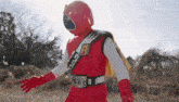 a person in a red superhero costume is standing in a field .