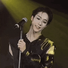a man in a black shirt is singing into a microphone on stage .