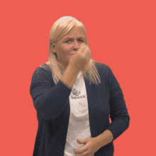 a woman covering her face with her hand while wearing a white shirt that says ' sa '