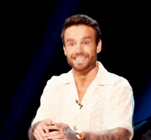a man with a beard wearing a white shirt with a microphone on it