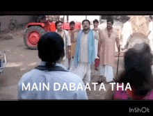 a group of people standing in front of a red tractor with the words `` main dabata tha '' written on the screen .