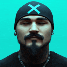 a man with a beard wearing a black beanie with a blue x on it