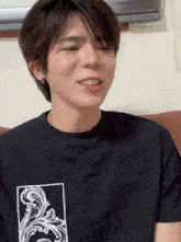 a young man wearing a black t-shirt with a white floral design on the front