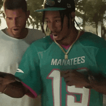 a man wearing a manatees jersey looks at a cell phone