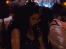 a group of people are dancing in a dark room with lights behind them