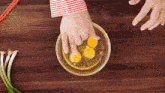 a person is cracking eggs into a bowl with chopsticks on a wooden table