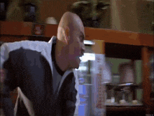 a bald man is standing in front of a shelf with a sign that says ' coca cola '