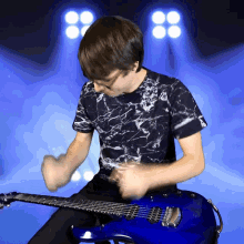 a young man is playing a blue electric guitar in front of a blue background