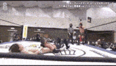two men are wrestling in a ring with a referee watching