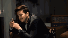 a man in a suit is sitting on a couch looking at his phone