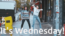 two women are dancing on a sidewalk with the words it 's wednesday