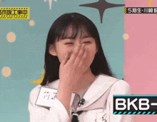a girl with a name tag that says bkb covering her mouth