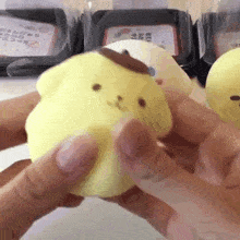 a person is holding a yellow squishy toy in their hand .