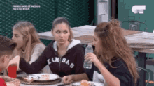 a group of people are sitting at a table eating food and drinking water .