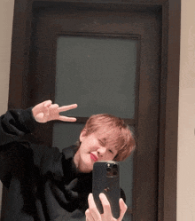 a person is taking a selfie with their phone and giving a peace sign