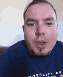 a man wearing a university of michigan shirt is making a face