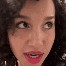 a close up of a woman 's face with curly hair and pink lipstick .