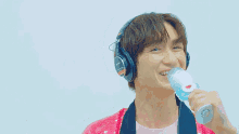 a man wearing headphones and a pink sequined jacket is singing into a microphone