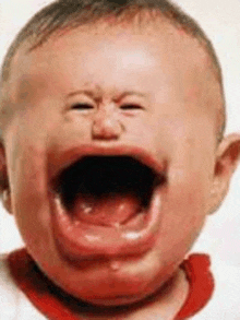 a baby is crying with his mouth wide open and his eyes closed .