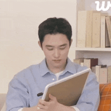 a man is sitting on a couch reading a book while holding a tablet