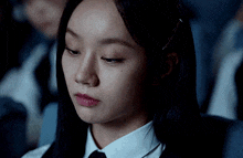 a close up of a woman 's face wearing a white shirt and black tie
