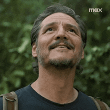 a man with a beard and mustache is smiling and looking up with a max logo behind him