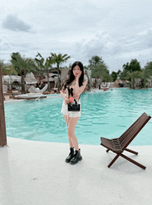 a woman stands in front of a swimming pool with a chair in the foreground