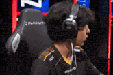 a man wearing headphones sits in a blacklyte gaming chair