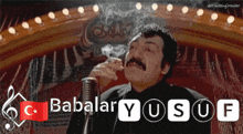 a man with a mustache is smoking a cigarette in front of a microphone with babalar yusuf written below him