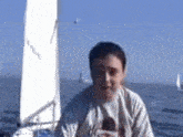 a man is sitting on a boat in the ocean with a sail that says ' i 'm sorry ' on it