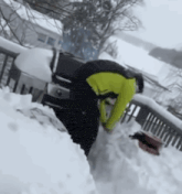 a man in a yellow jacket is clearing snow from a grill