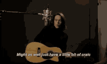 a man is playing an acoustic guitar in front of a microphone in a recording studio .