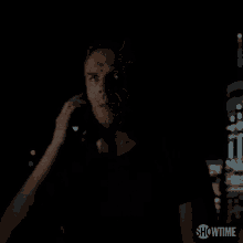 a man is talking on a cell phone in the dark with showtime written on the bottom of the screen .