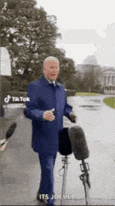 a man in a suit is talking into a microphone while walking down a street .