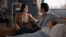 a man and a woman sitting next to a boy in a hospital bed