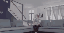 a man is sitting on a couch in a living room with stairs behind him .