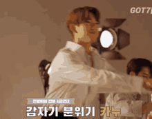 a man in a white shirt is standing in front of a light with the word got7 on the bottom right