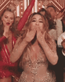 a woman in a dress is blowing a kiss while dancing in a crowd .