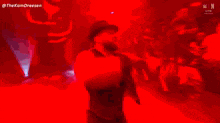 a man in a hat is singing into a microphone on a stage in a dark room .